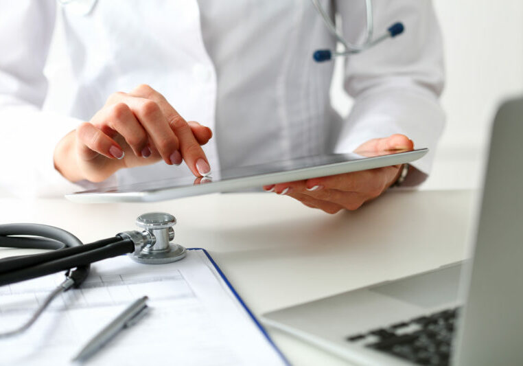 Female doctor hold digital tablet pc and point in touch screen with finger closeup.